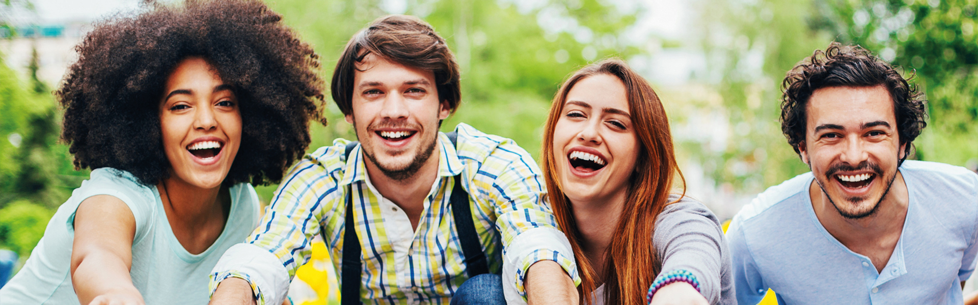 Vier junge fröhliche Menschen lachen in die Kamera